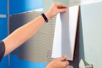 Pose de carrelage sur un mur en plaques de plâtre dans une salle de bain