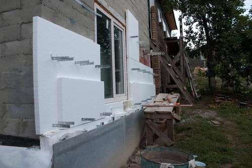 Nous construisons une maisonIsolation d'une maison en bois à l'extérieur avec du plastique mousse avec nos propres mains sous le revêtement